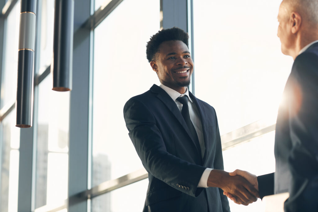 Two business professionals shaking hands in a modern office setting.